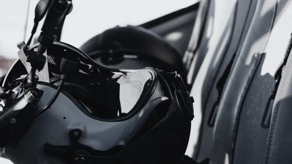 A pilot's flight helmet with its visor and boom microphone, resting on a helicopter seat