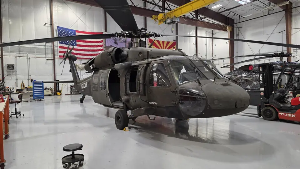 UH-60 Black Hawk in a hangar under the US and Arizona flags, a second Black Hawk in a star livery behind it