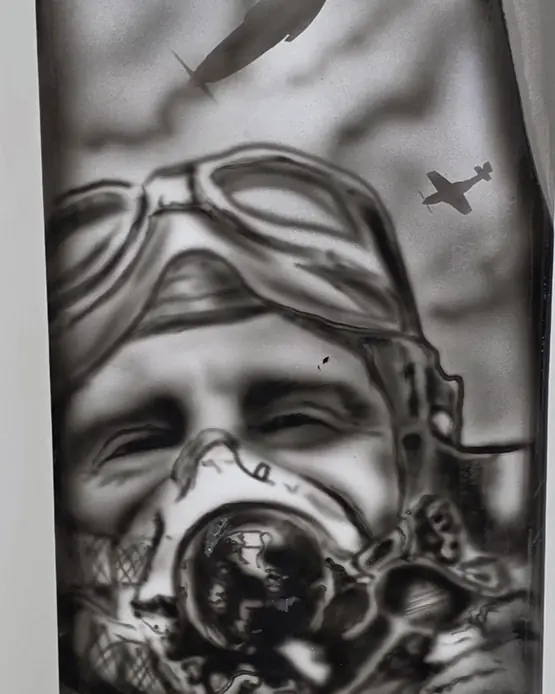 Detail of a painted propeller blade: a vintage pilot in goggles and an oxygen mask, with fighter aircraft in the sky above