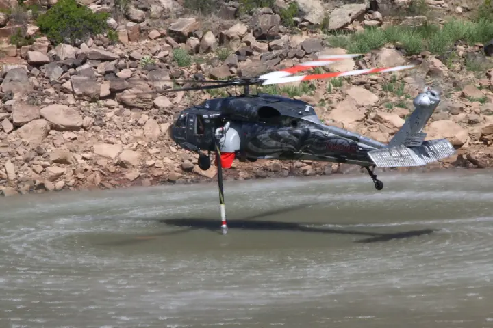 Castleberry UH-60 Black Hawk in its star livery hovering low over a lake below a rocky shore
