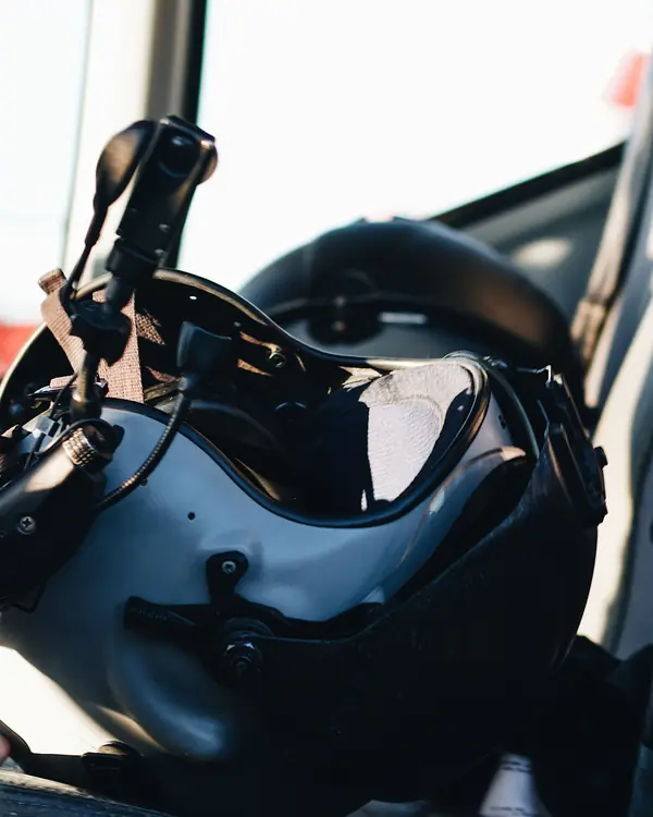 A pilot's flight helmet with its visor and boom microphone, resting on a helicopter seat