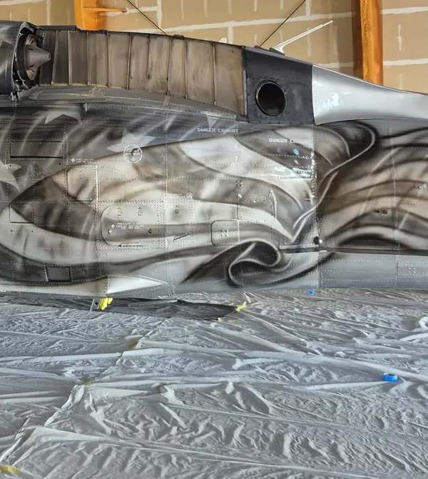 Flag-and-eagle artwork in progress on a UH-60 Black Hawk's tail section in the CAS paint hangar